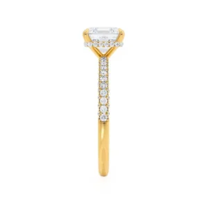 This elegant princess cut triple pavé shoulder set engagement ring features a glittering secret hidden halo that can only be seen from the side profile, adding extra sparkle to the best selling solitaire. Crafted in luxurious 18k Yellow Gold this ring truly glitters from every angle.