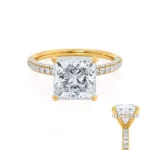 This elegant princess cut triple pavé shoulder set engagement ring features a glittering secret hidden halo that can only be seen from the side profile, adding extra sparkle to the best selling solitaire. Crafted in luxurious 18k Yellow Gold this ring truly glitters from every angle.